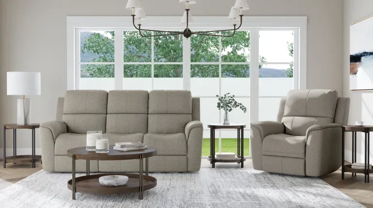 Living room with gray couch and gray recliner in front of a large window reaching all the way to the floor